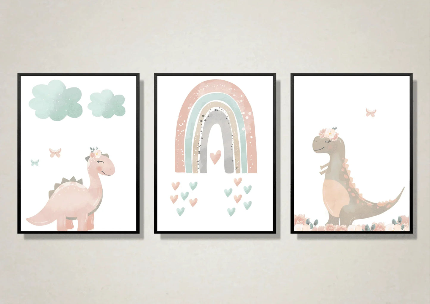 A trio of digital art prints for a nursery, each framed in a black frame. The first print on the left features a smiling, pastel pink dinosaur with a floral crown, standing under two light blue clouds with two butterflies nearby. The middle print shows a pastel rainbow with a heart at its base and smaller hearts floating below. The third print on the right features a brown dinosaur with a floral crown, standing in a field of flowers, with a butterfly flying above.