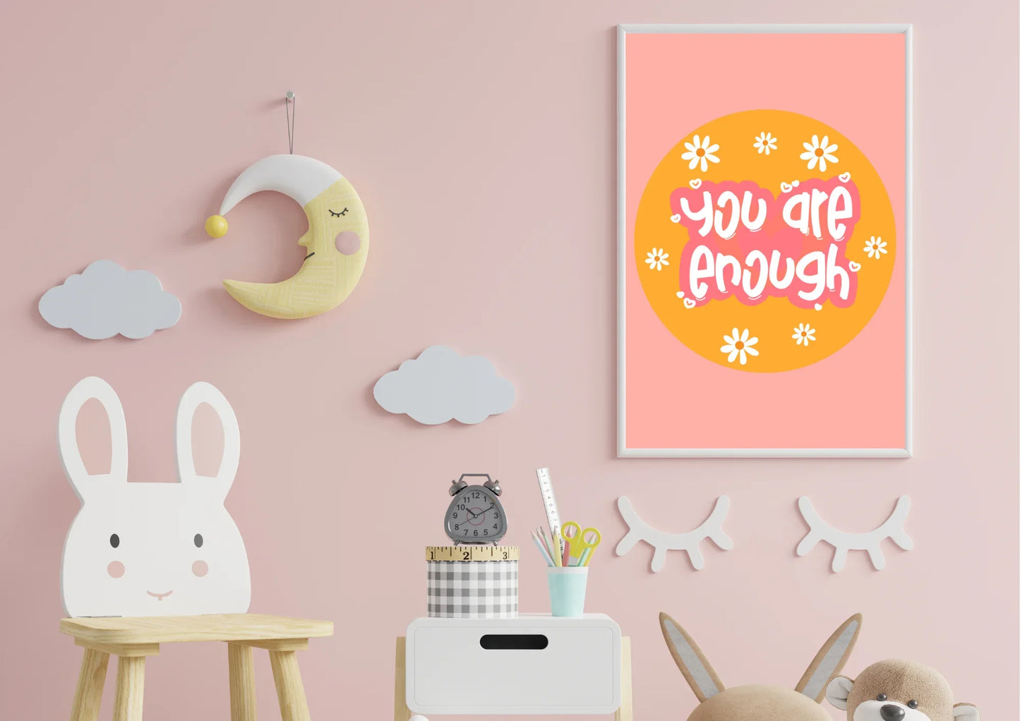Children's room with decorative items on a pink wall, including a moon, clouds, and a motivational poster.