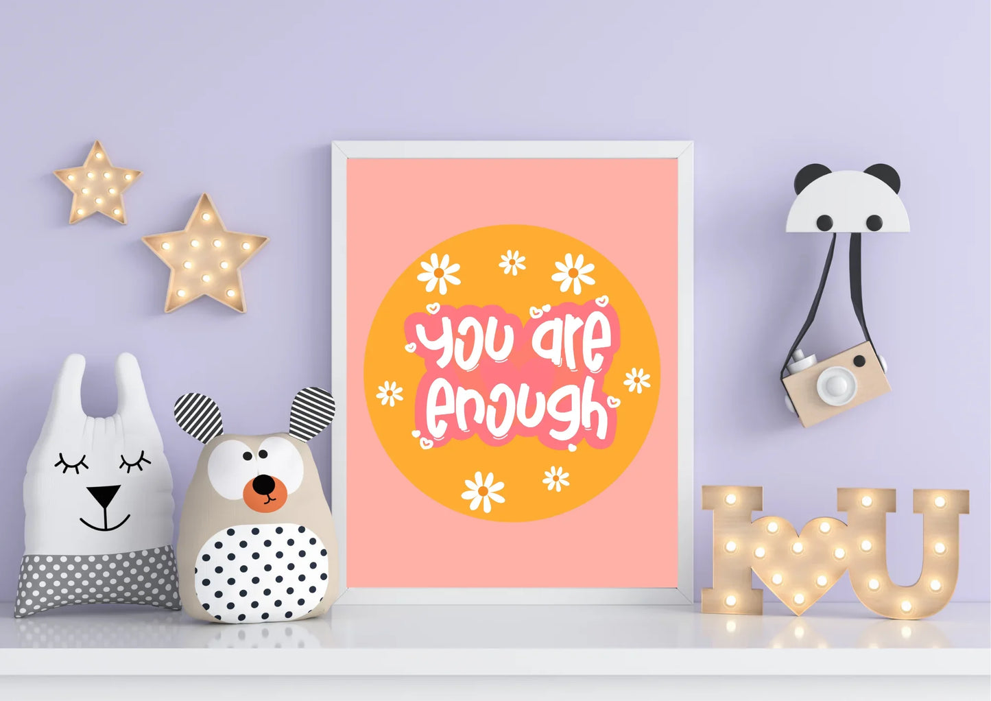 Decorative wall art with 'You are enough' quote, surrounded by cute animal plush toys and light-up letters on a purple wall.