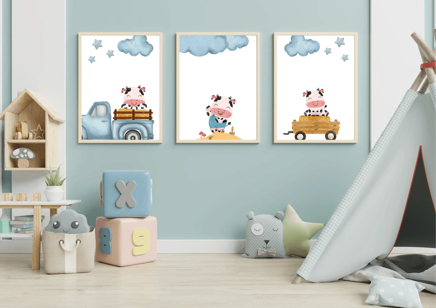 Three framed Farm Cow Nursery Art prints over colorful play blocks and a teepee tent in a light blue kids room.