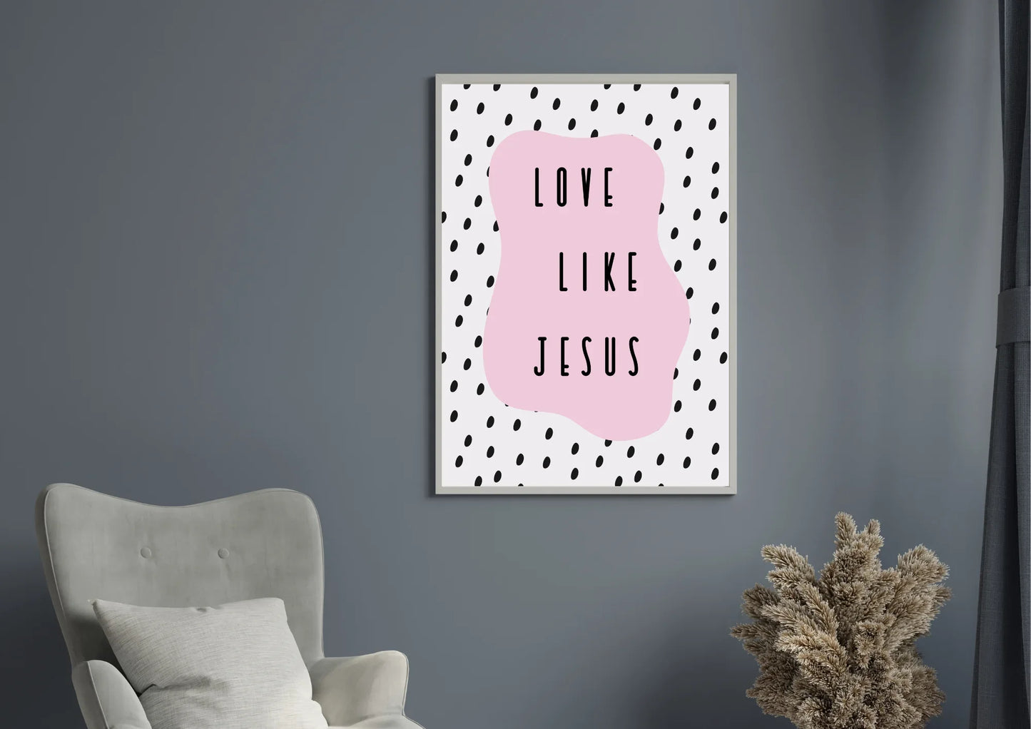 A framed art print with the quote "Love like Jesus" on a pink background, hanging on a gray wall in a modern living room.