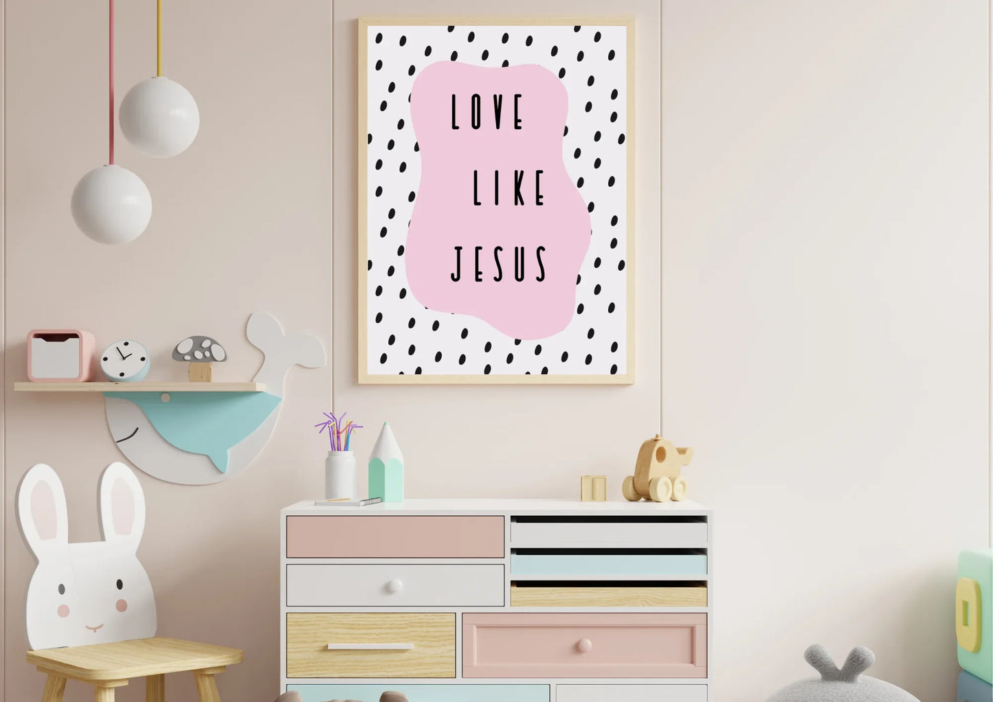 A wooden-framed art print with the quote "Love like Jesus" on a pink wall above a dresser in a child's bedroom