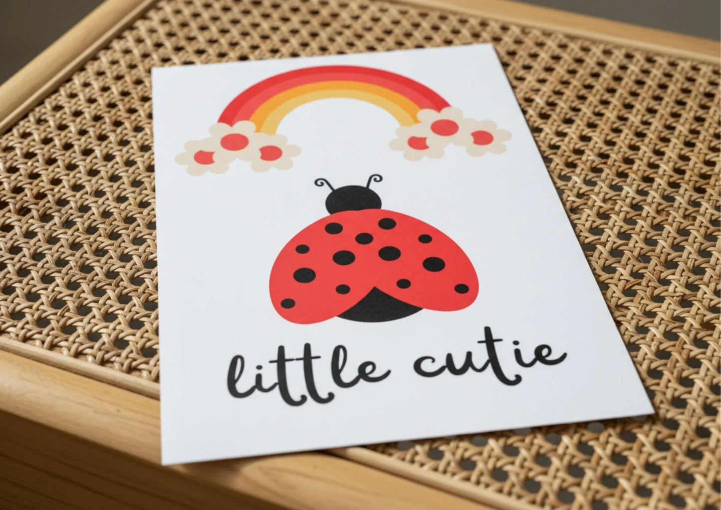 Card with a ladybug and rainbow illustration on a woven surface