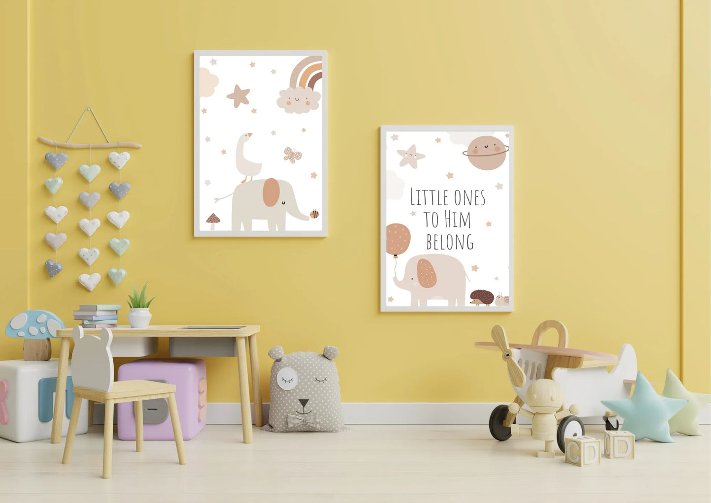 A set of two framed art prints with elephants and the quote "Little ones to him belong" on a yellow wall in a child's playroom.