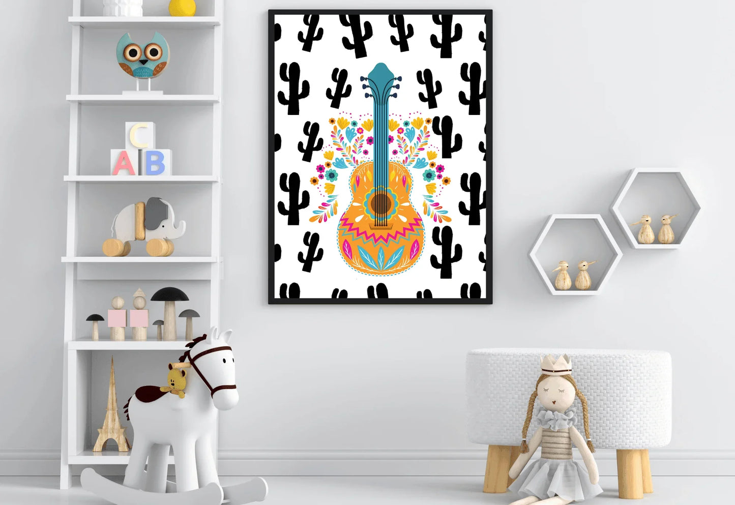 A framed boho folk art guitar print with a black cactus background, hanging on a white wall in a nursery with a bookshelf, a rocking horse, and a doll.