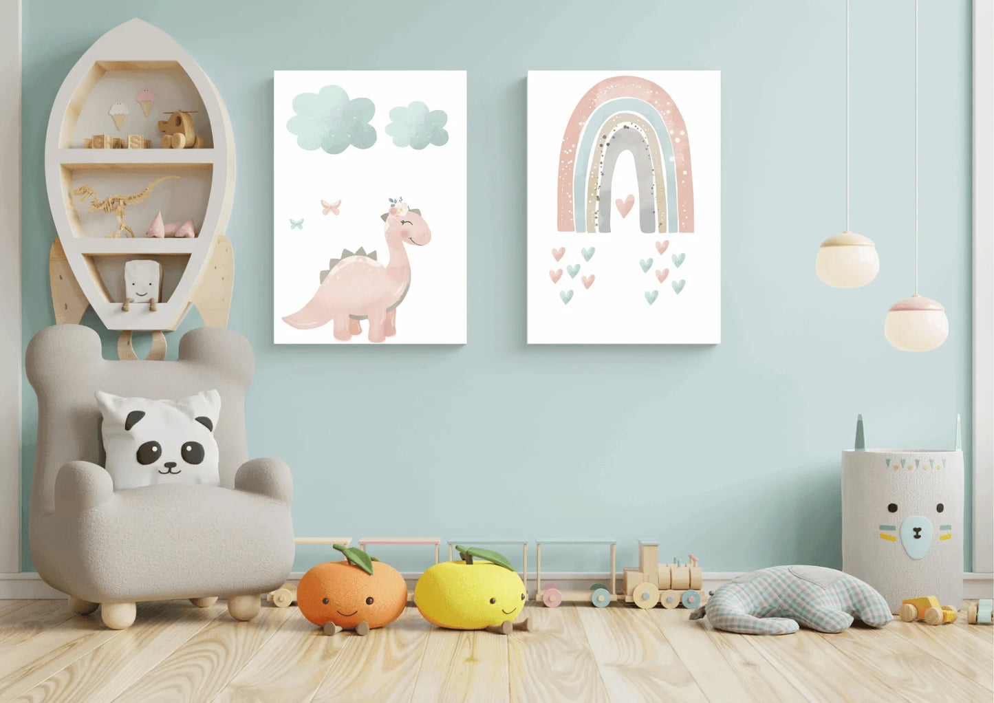 Two framed pastel prints (pink dinosaur with clouds, and a rainbow with hearts) on a light blue wall in a child's playroom with a rocket shelf.