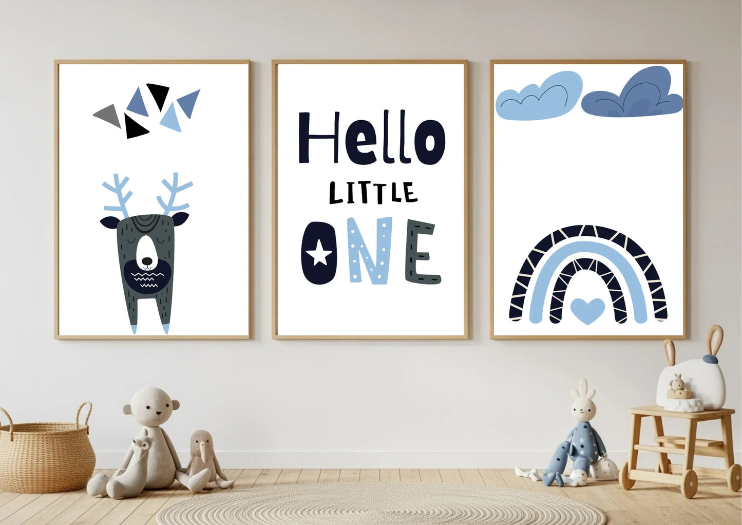 Three framed prints on a wall with toys below, featuring a deer, text, and rainbow designs.