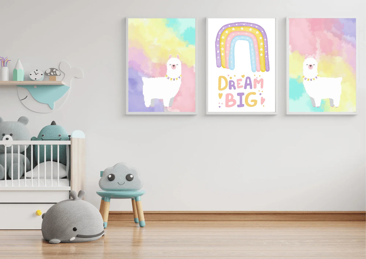 A set of three framed art prints with two llamas and a "Dream Big" quote on a white wall in a child's playroom with a crib and toys.