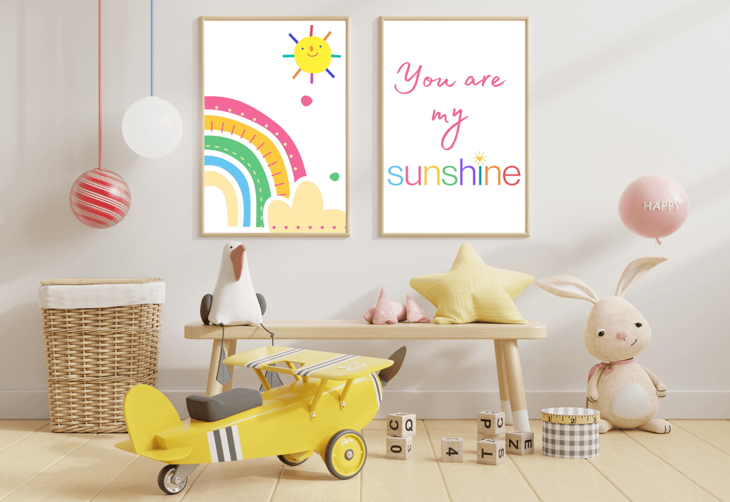 A vibrant child's room with a light blue wall. On the wall, two framed prints show a cheerful, colorful rainbow with a smiling sun and a text print that reads "You are my sunshine" in bright pink and rainbow colors.