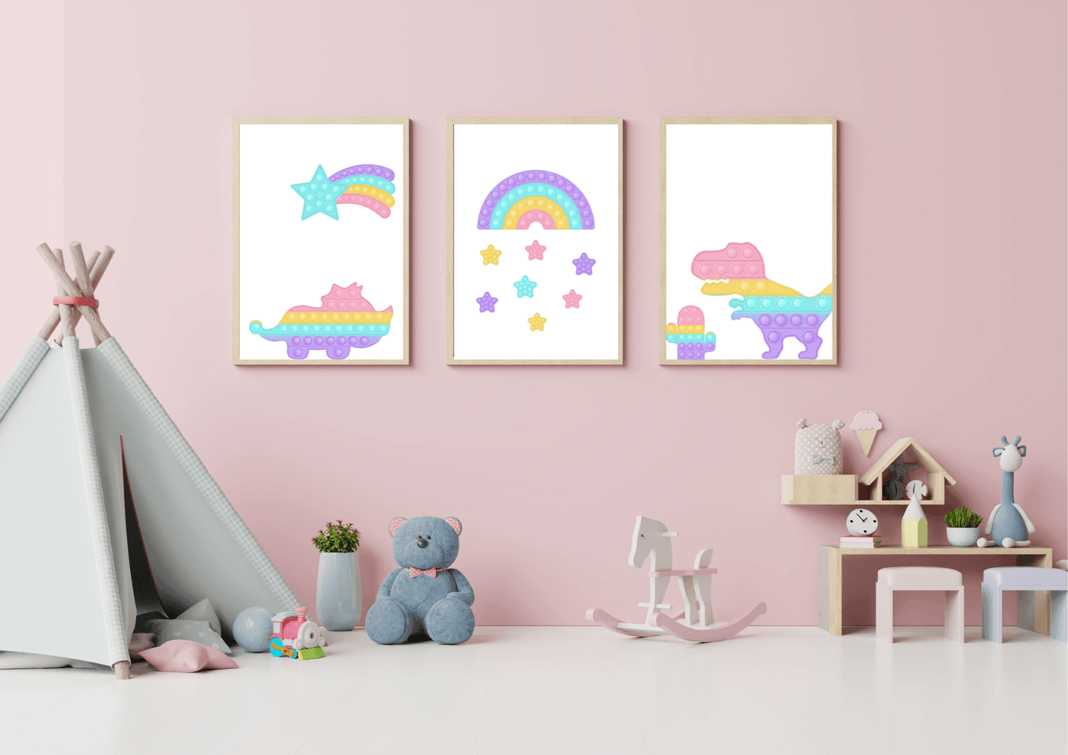 A kid's room with a pink wall and a teepee tent. Three framed pop-art style prints hang above a small shelf, featuring a Tyrannosaurus Rex and a rainbow made of colorful circles, and a shooting star.