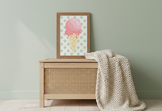 Wooden chest with a blanket draped over it, next to a framed picture of an ice cream cone on a light green wall.