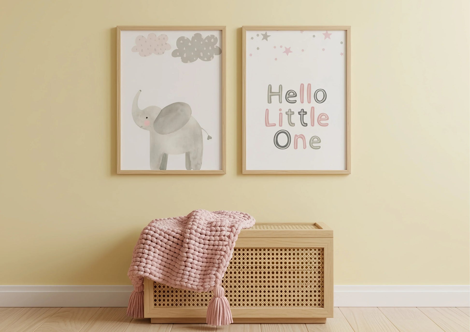 Two framed pictures on a wall with a pink blanket and wooden basket below.