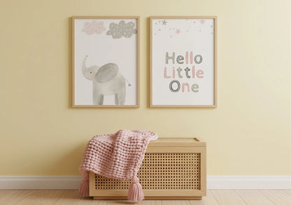Two framed pictures on a wall with a pink blanket and wooden basket below.