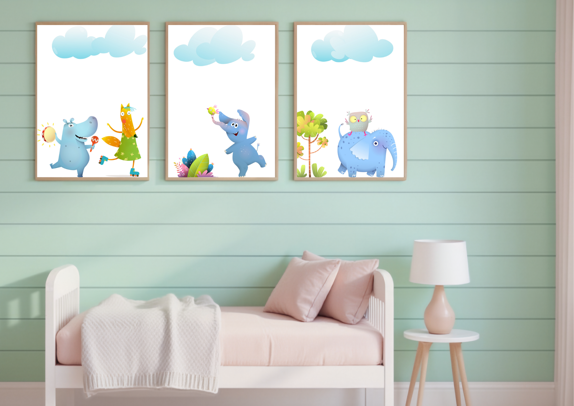 
A set of three whimsical animal art prints with wooden frames on a green plank wall above a daybed in a child's bedroom.