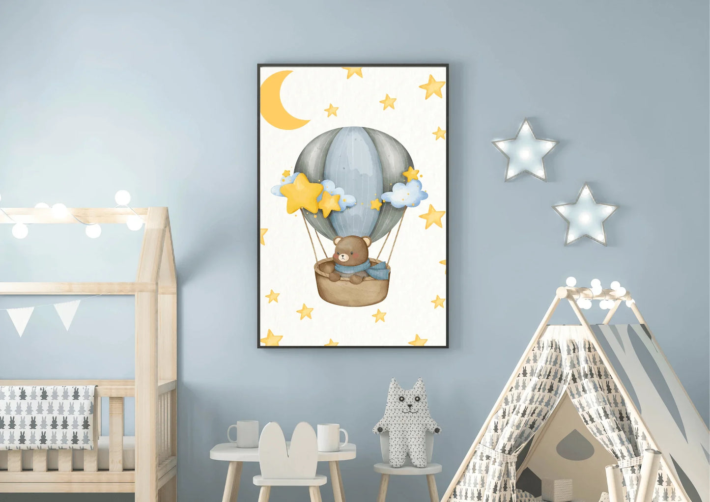 Framed bear hot air balloon wall art in a blue themed baby room next to a wooden toddler bed and a canvas play tent.