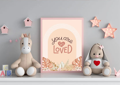 
A framed "You are so LOVED" boho art print on a shelf with stuffed animals and pink star lights.