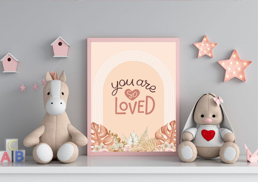 
A framed "You are so LOVED" boho art print on a shelf with stuffed animals and pink star lights.