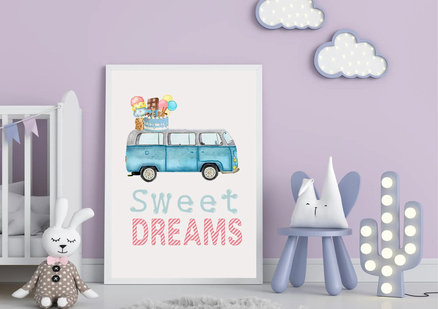 A large framed art print is centered against a light lavender wall in a child's room. The artwork is a watercolor illustration of a blue, vintage Volkswagen van (VW bus) with a stack of ice cream cones, popsicles, and a birthday cake on its roof. Below the image, the text "Sweet DREAMS" is written in a playful light blue and striped pink font.
