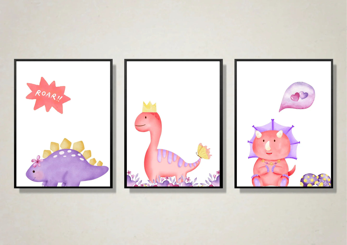 A set of three framed digital art prints featuring watercolor dinosaurs. The left print shows a purple stegosaurus with a speech bubble that says "ROAR!!", the middle print is a pink dinosaur with a crown, and the right print shows a pink and purple triceratops with a heart bubble. The prints are framed in black frames and hang on a light, textured wall.