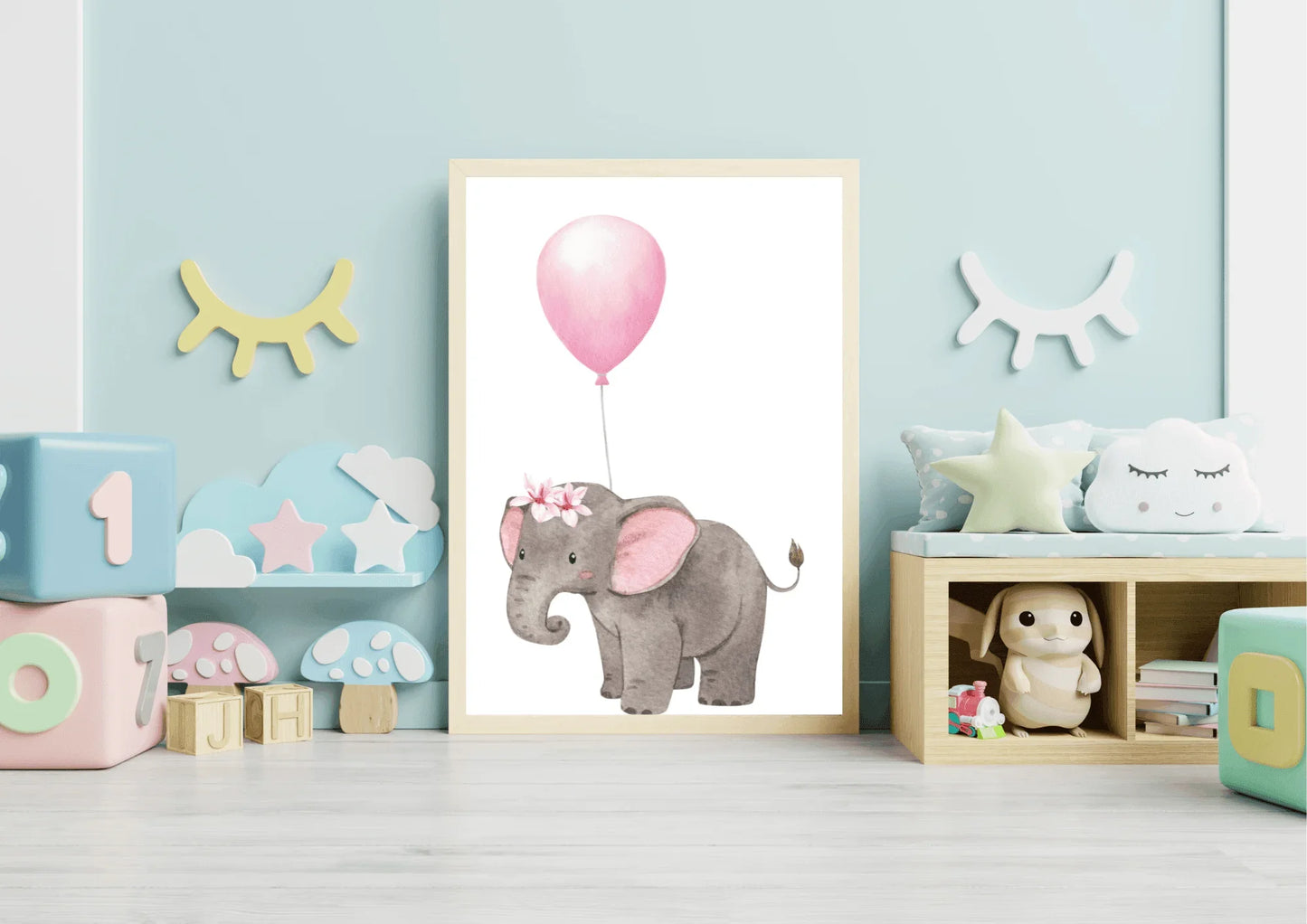 A framed nursery print of a baby elephant with a floral crown holding a pink balloon, standing on a light blue wall between two shelves with children's toys and decor.
