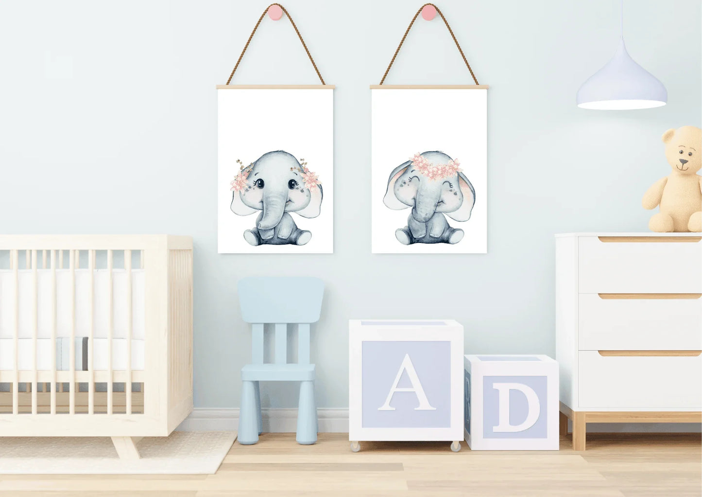 Image Description|Elephant Print Nursery Mockup
A cozy, stylish nursery room featuring a light grey accent wall with a playful pattern of white clouds. Two matching light wood-framed watercolor elephant prints are hung above a low white wooden dresser or change table. The elephants are soft grey with delicate pink flower crowns. To the right, a large white wooden crib is partially visible. The room uses soft pinks, light grey, and natural wood tones to create a gender-neutral, cloud-and-animal themed space.