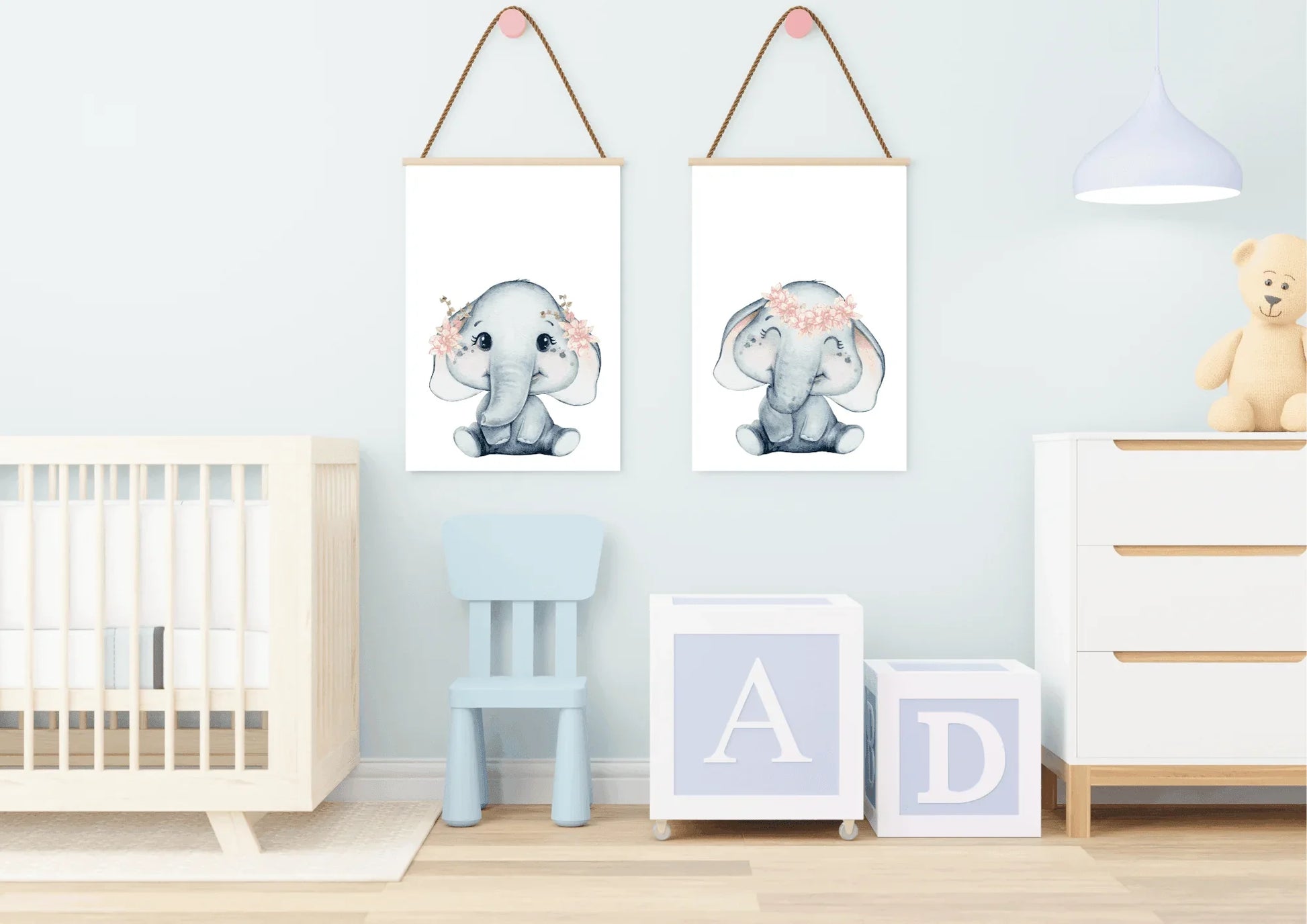 Image Description|Elephant Print Nursery Mockup
A cozy, stylish nursery room featuring a light grey accent wall with a playful pattern of white clouds. Two matching light wood-framed watercolor elephant prints are hung above a low white wooden dresser or change table. The elephants are soft grey with delicate pink flower crowns. To the right, a large white wooden crib is partially visible. The room uses soft pinks, light grey, and natural wood tones to create a gender-neutral, cloud-and-animal themed space.