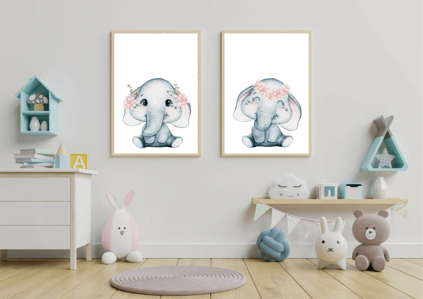 A modern room interior featuring a white wooden dresser or low cabinet. The wall behind the dresser is painted a neutral light taupe or beige. Two white-framed watercolor elephant prints are hung side-by-side above the dresser. The soft grey elephants are adorned with delicate pink flower crowns. The dresser surface holds a stack of children's books, and the floor features a round woven jute rug.