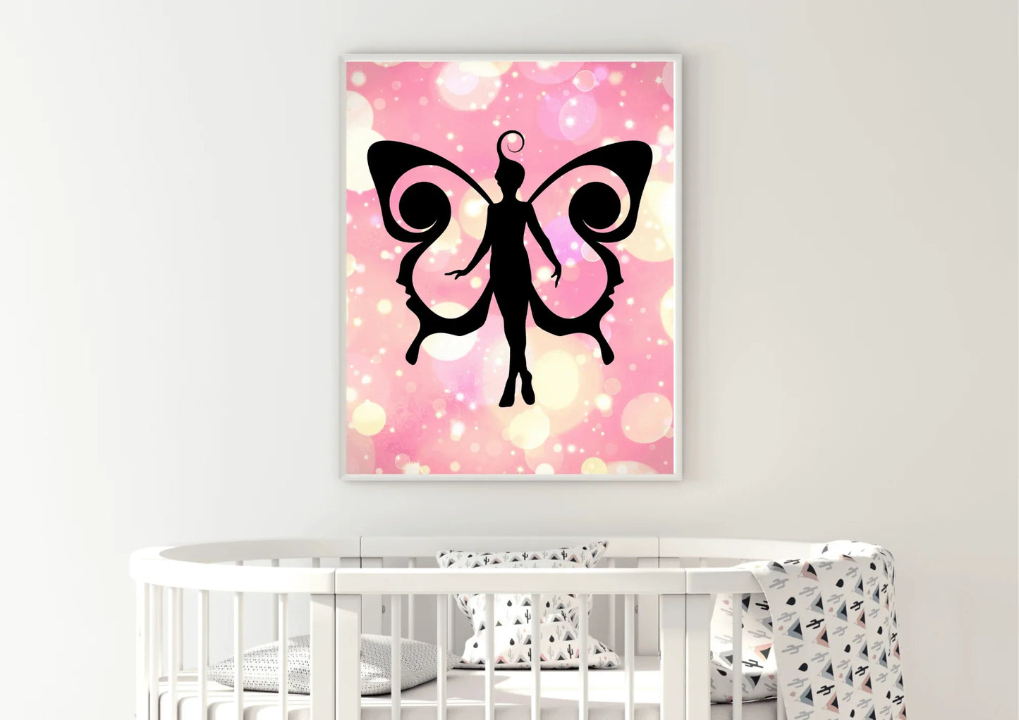 Framed artwork of a black fairy silhouette on a pink and white abstract background above a crib.
