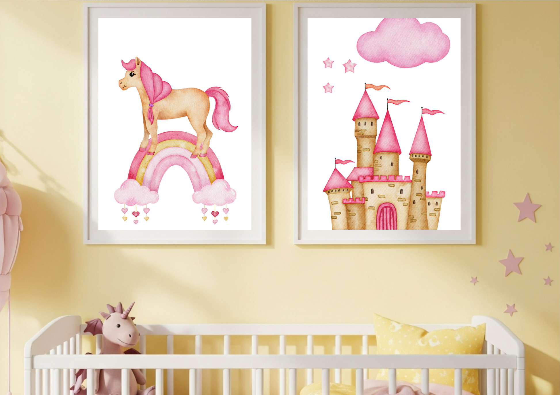 A set of two framed watercolor prints hanging on a pale yellow wall above a white crib. The left print features a pink and tan unicorn standing on a pink rainbow with heart-shaped clouds. The right print features a tall pink princess castle under a fluffy pink cloud