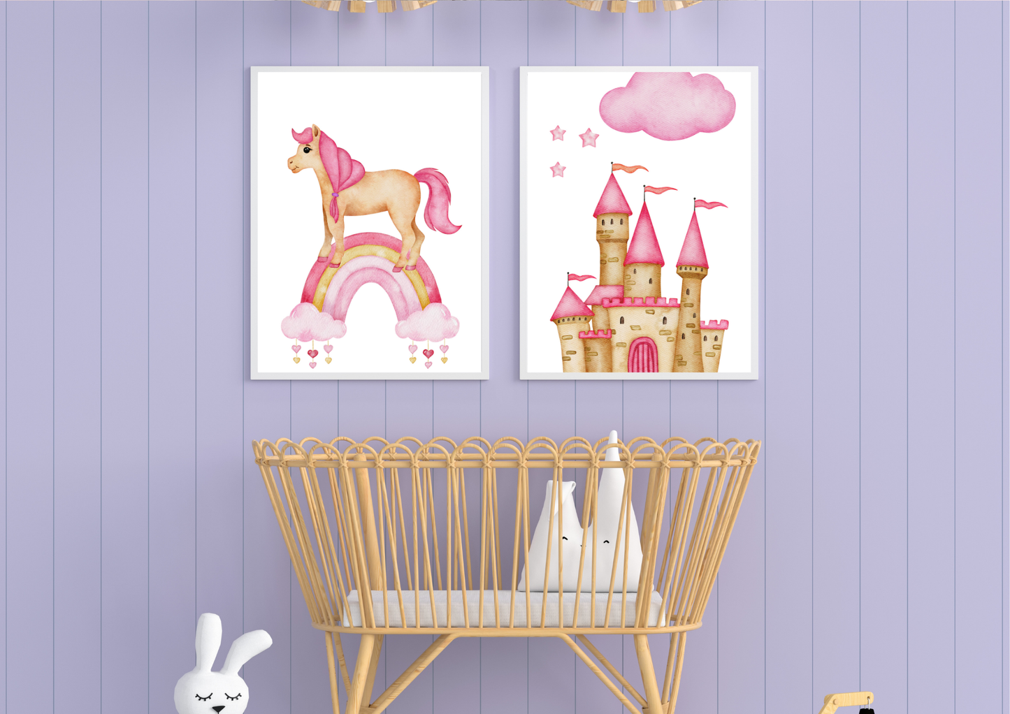 Two framed watercolor prints featuring a unicorn on a rainbow and a pink princess castle hang above a light wood bassinet. The background is a soft lavender wood paneled wall.