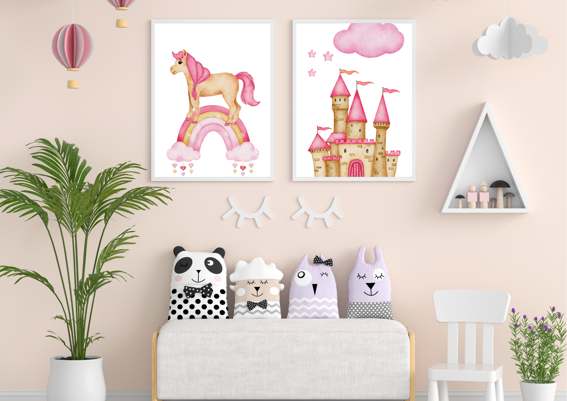 Two framed watercolor prints, one showing a unicorn on a rainbow and the other a pink princess castle, hang on a soft pink wall. Below the art, four animal-themed pillows rest on a white bench. To the left is a tall green houseplant, and to the right is a white triangular shelf with small wooden figures.