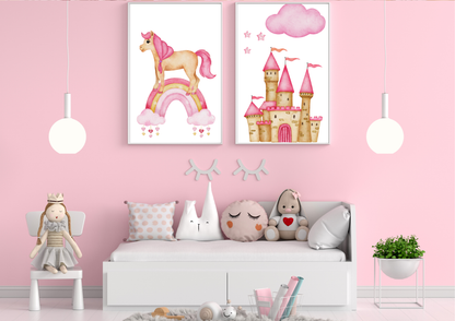 Two framed watercolor prints featuring a unicorn on a rainbow and a pink princess castle hang on a bright pink wall. Two white pendant lights hang on either side of the art. Below the prints is a white daybed with several decorative pillows, and a small doll sits on a white chair to the left.