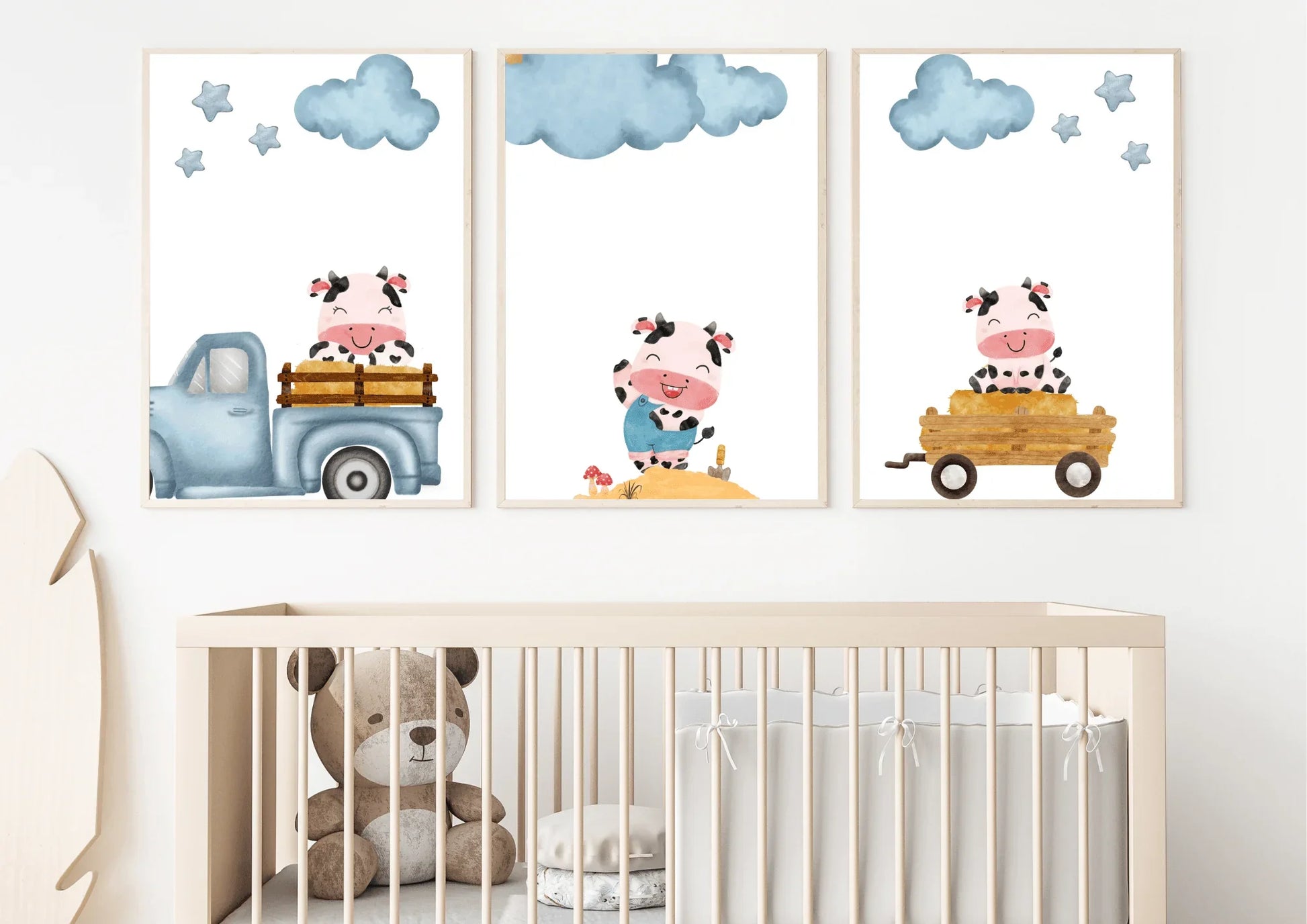 Close-up of three framed Farm Cow Nursery Art prints displayed over a light wooden crib in a neutral room.