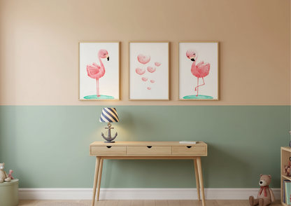 Three flamingo prints on a wall above a wooden console table with a lamp and toys.