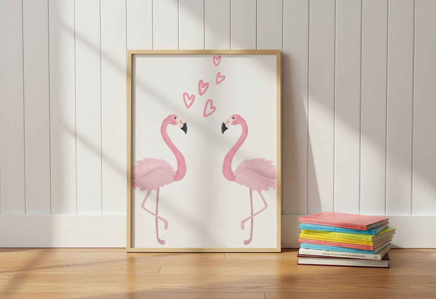 Framed artwork of two pink flamingos on a wooden floor with books in the background.
