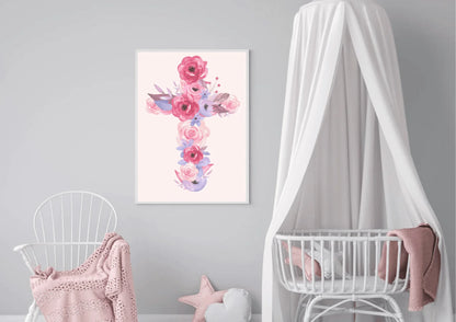 A baby nursery with a light gray wall. A framed art print of a cross made of pink and purple watercolor flowers hangs in the center. A white crib with a sheer canopy is on the right, and a curved chair with a pink blanket is on the left.