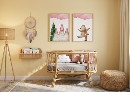 Two framed watercolor winter bear art prints above an oval rattan bassinet in a warm yellow nursery.