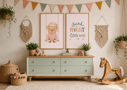 A styled nursery interior featuring two framed wall art prints above a mint green and wood dresser. The left print shows a cartoon pig in a pink hat, and the right print reads 'good NIGHT little one' in colorful lettering.