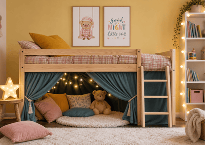 A wooden loft bed in a cozy children's bedroom, styled with teal curtains, fairy lights, pillows, a teddy bear, and two framed wall prints. The room has a warm yellow wall and a white bookshelf with string lights.
