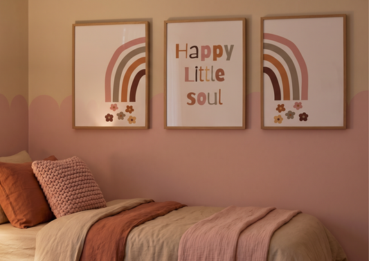 Three framed prints on a wall above a bed with colorful bedding.