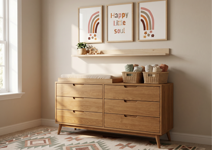 Wooden dresser in a nursery with framed artwork and decorative items.