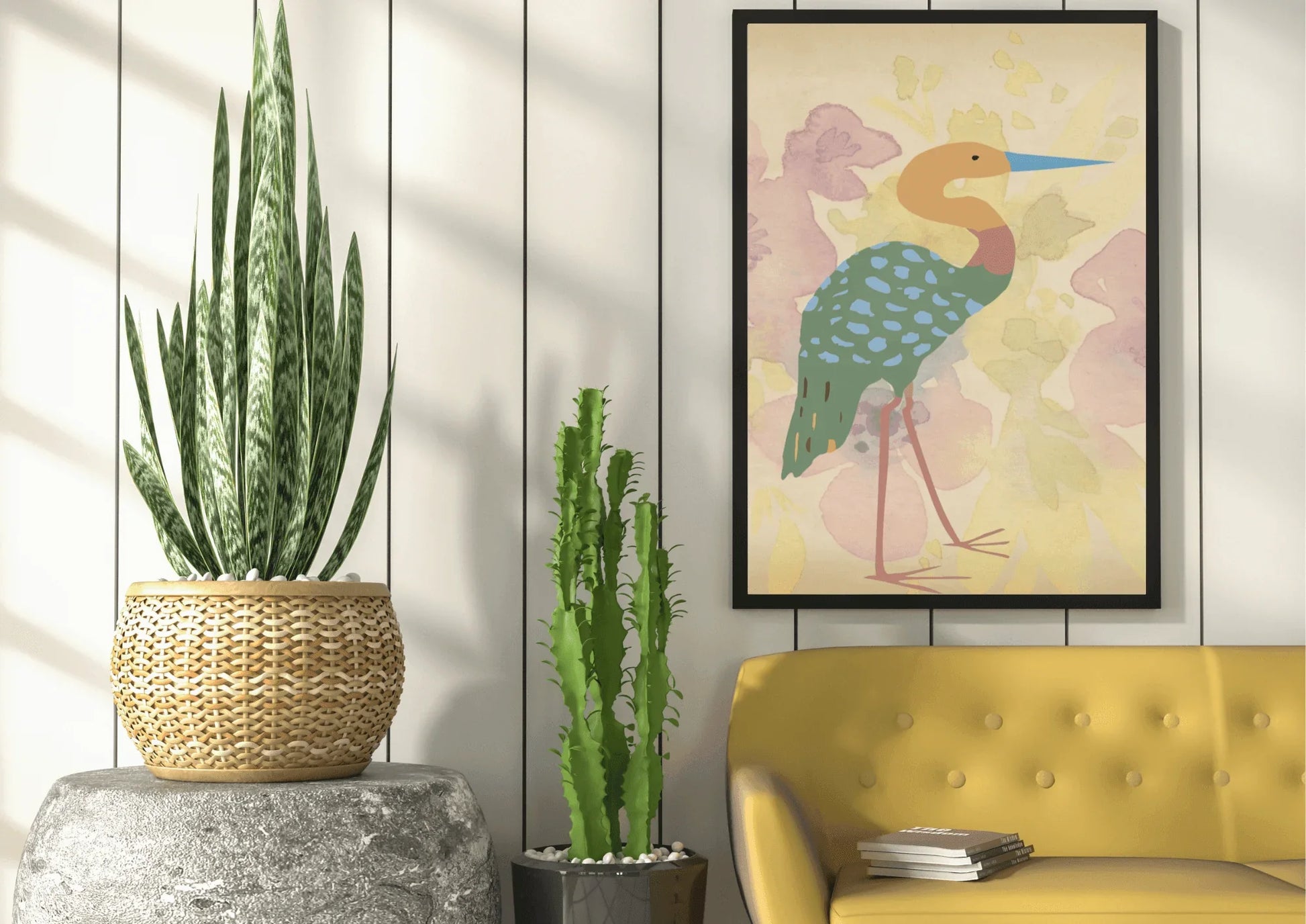 
A framed digital art print of a stylized heron, with a blue beak and a turquoise, spotted body, hanging on a white plank wall above a yellow couch. A large snake plant in a woven pot sits on a gray pedestal and a thin cactus stands next to it.