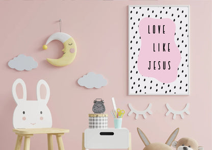 
A framed "Love like Jesus" art print on a pink wall in a child's nursery with a sleepy moon and clouds.