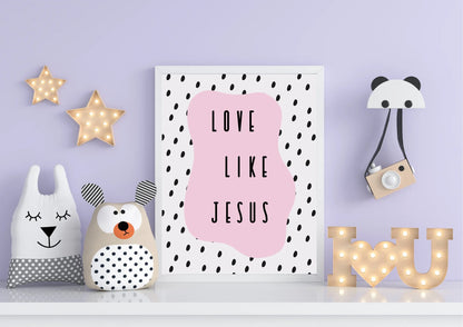 A framed "Love like Jesus" art print on a shelf with pillows and light-up stars on a light purple wall.