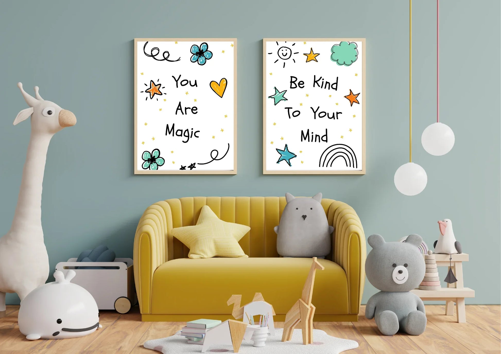 A pair of framed digital art prints with whimsical doodles and motivational quotes, hanging on a blue wall above a yellow couch in a child's room. The left print says "You Are Magic" and the right says "Be Kind To Your Mind." A large stuffed giraffe and various other toys are on the floor.