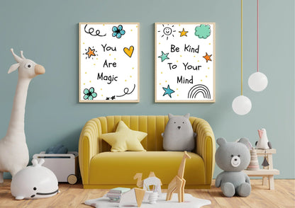 A pair of framed digital art prints with whimsical doodles and motivational quotes, hanging on a blue wall above a yellow couch in a child's room. The left print says "You Are Magic" and the right says "Be Kind To Your Mind." A large stuffed giraffe and various other toys are on the floor.