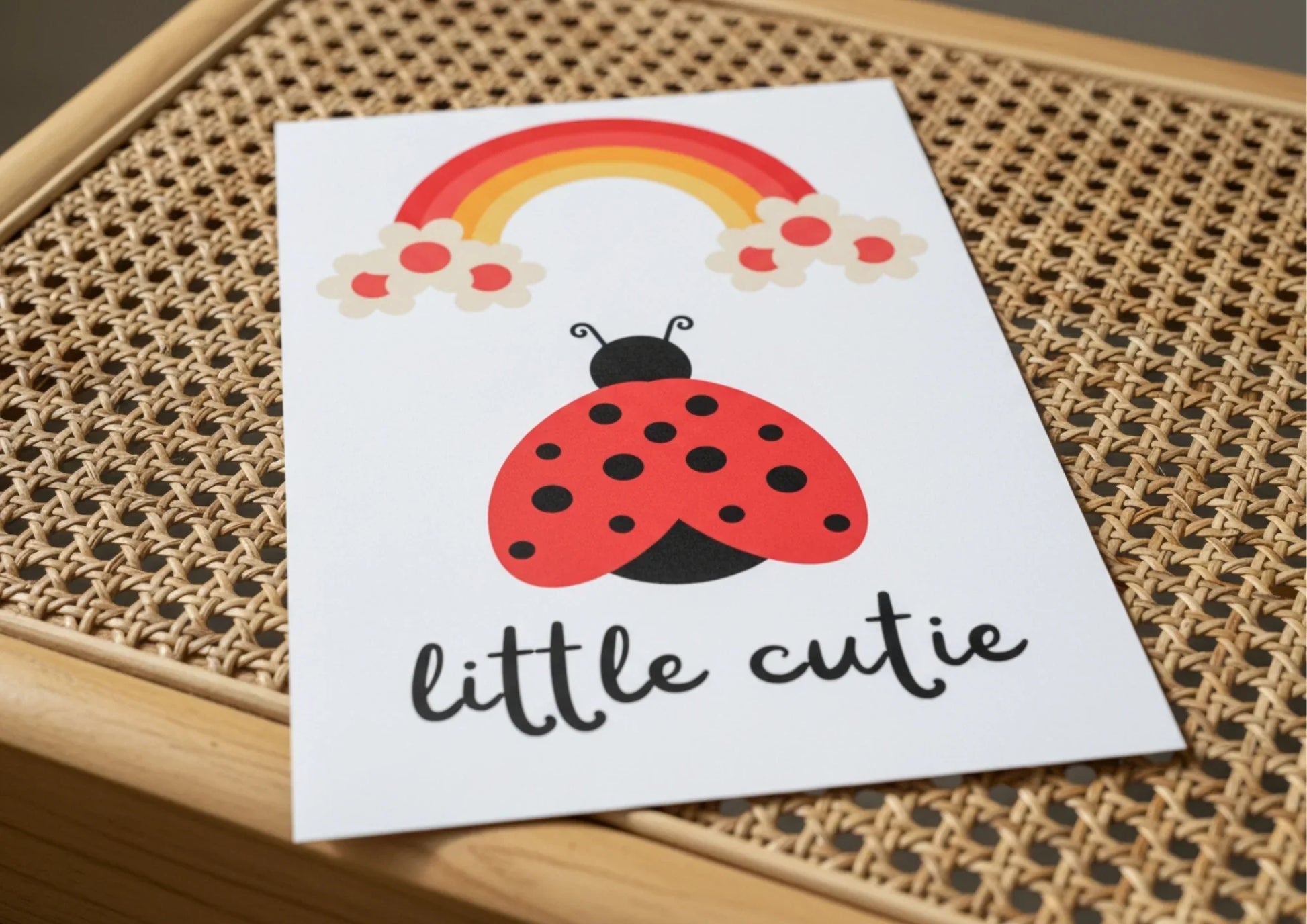 Card with a ladybug and rainbow illustration on a woven surface