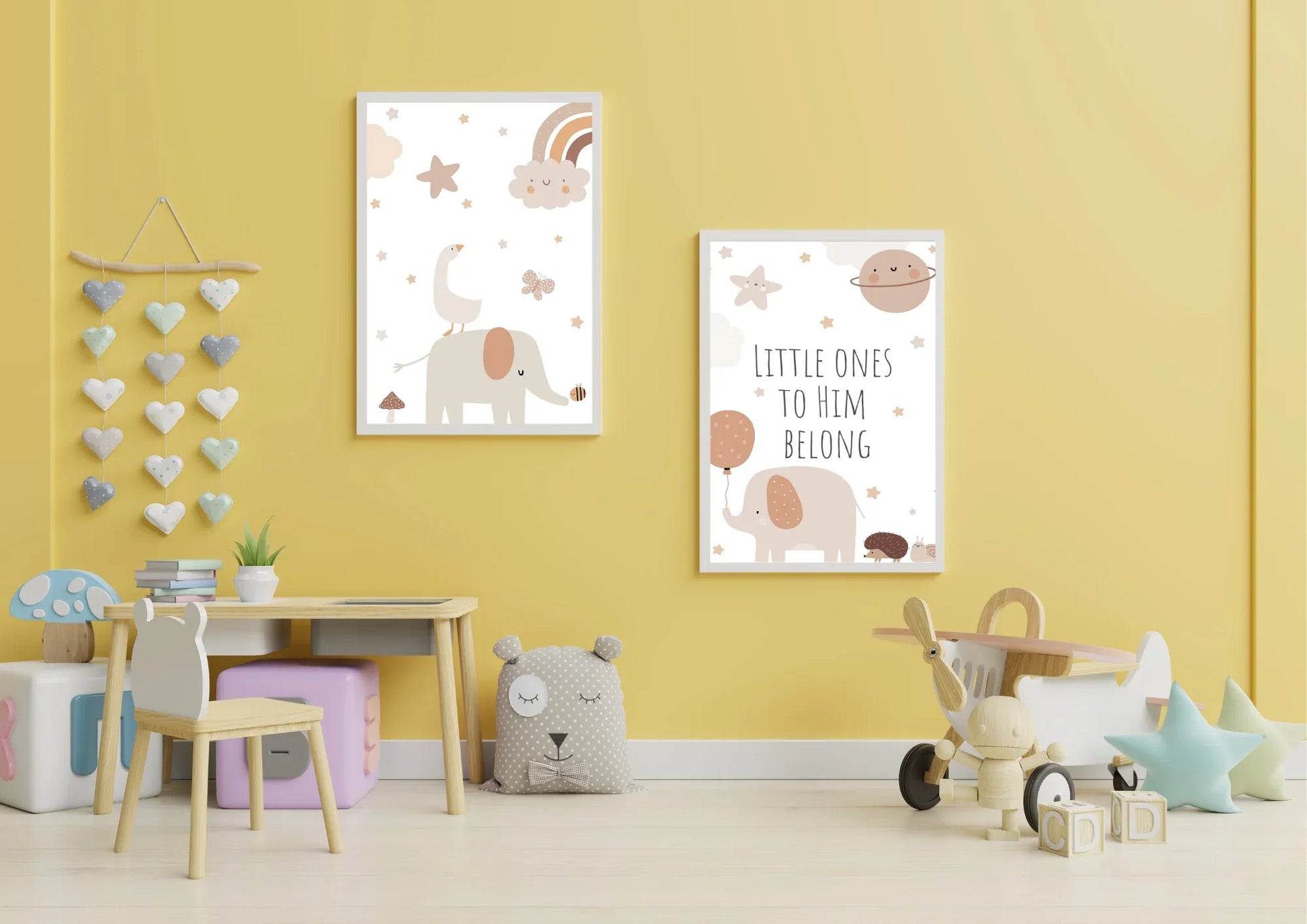 A set of two framed art prints with elephants and the quote "Little ones to him belong" on a yellow wall in a child's playroom.