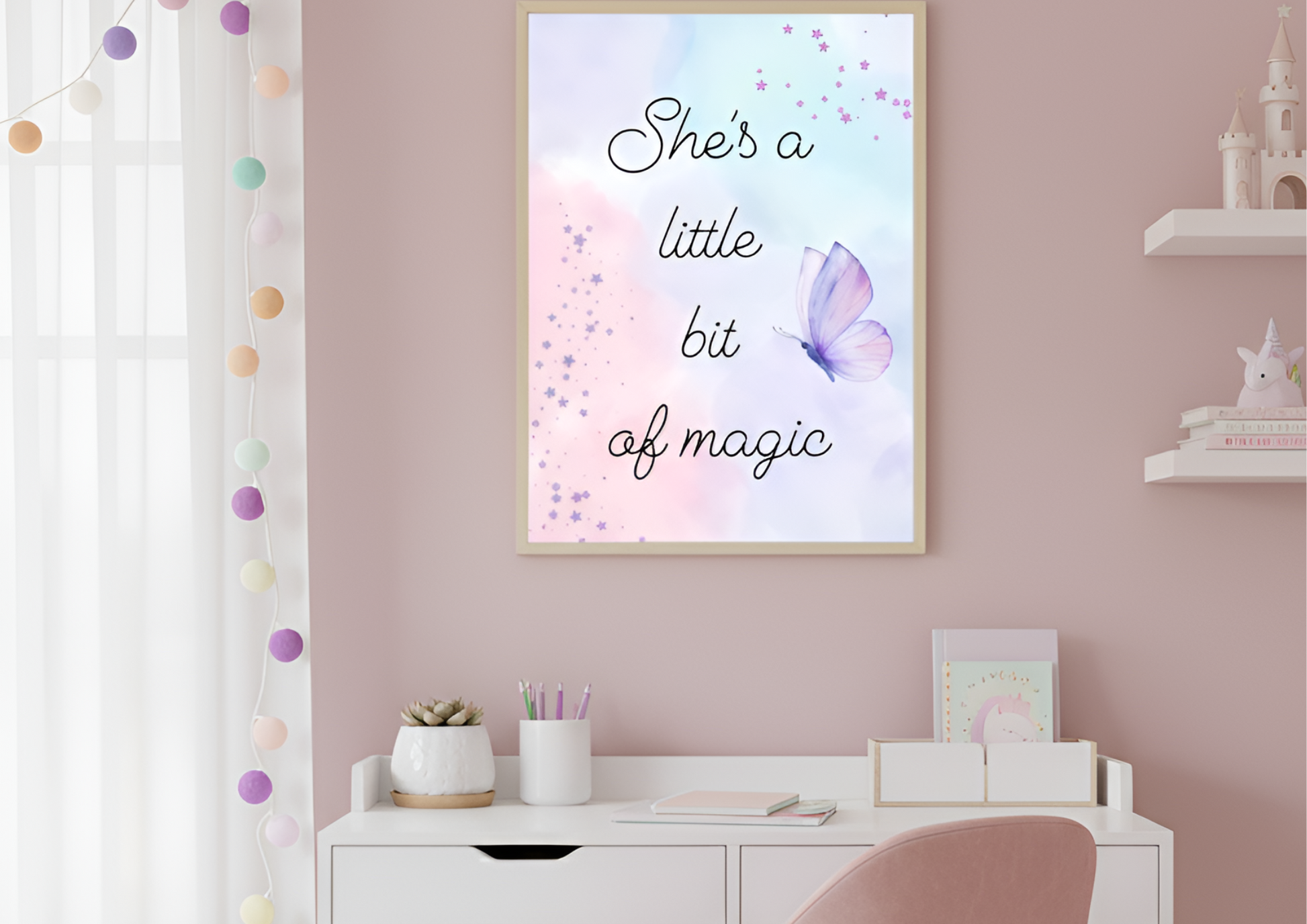 
A charming girl's bedroom with a two-toned pink wall. A white desk with wooden legs is against the wall, and a light pink chair with a velvet texture is tucked beneath it. A framed art print with a watercolor background and the words "She's a little bit of magic" hangs above the desk. The desk is organized with pens, a small plant, and a notebook. Two white floating shelves on the right hold decorative items, including a fairytale castle and a unicorn.