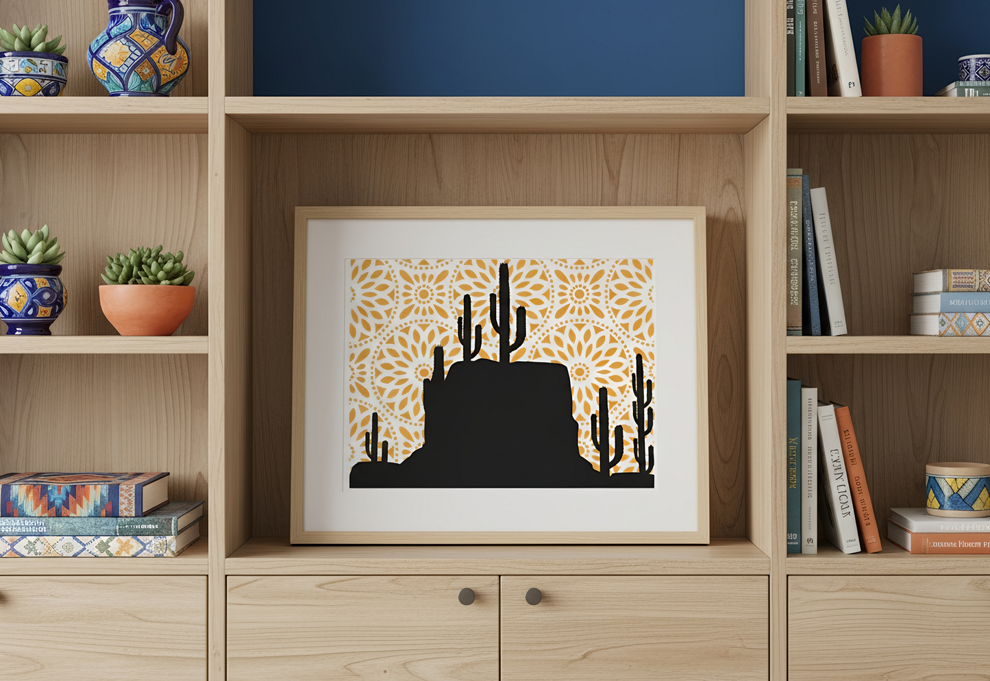 Framed artwork of a desert scene with cacti on a wooden shelf with decorative items.